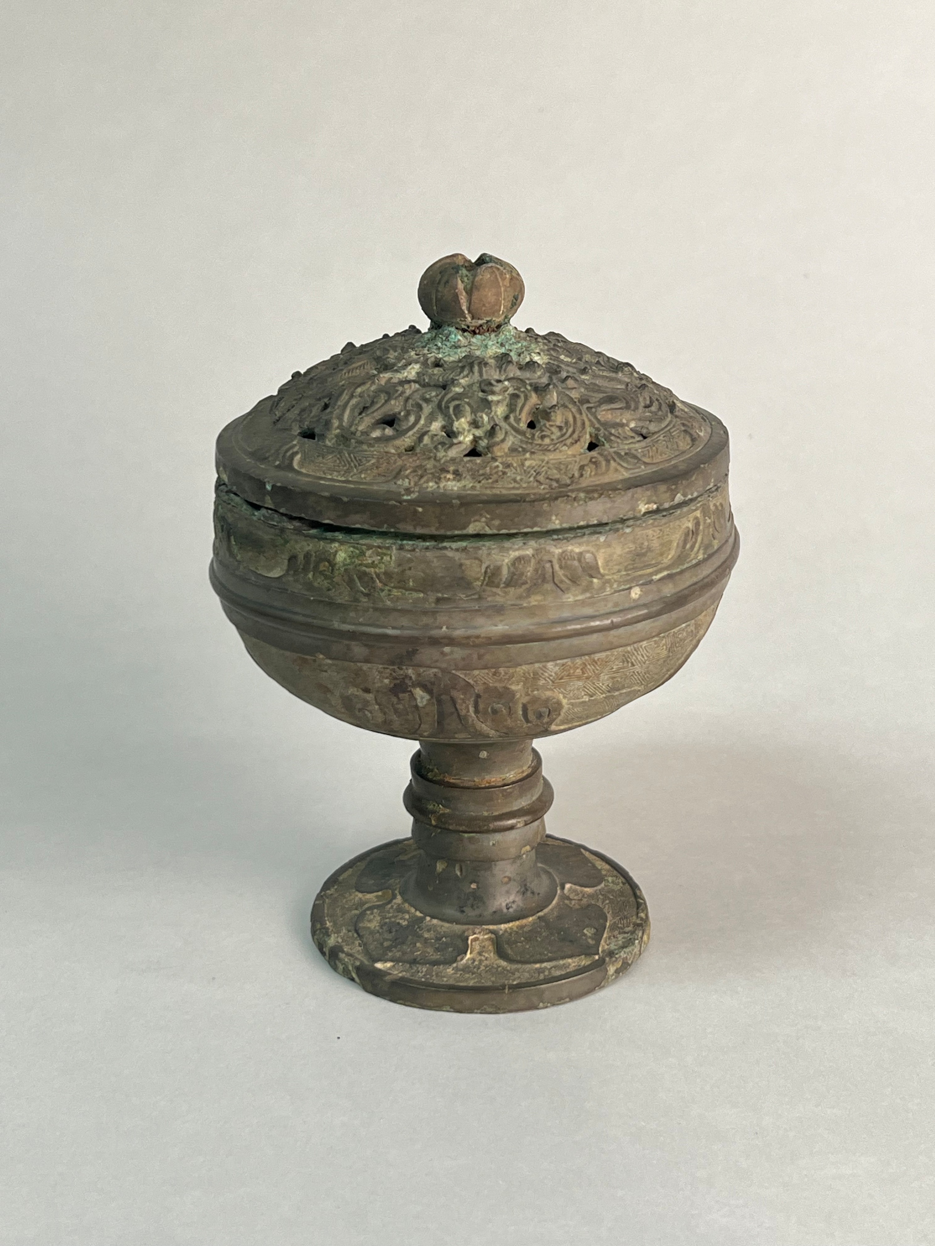 Petit brûle-parfum chinois en bronze sur pied, couvercle ajouré surmonté d'un fleuron.
