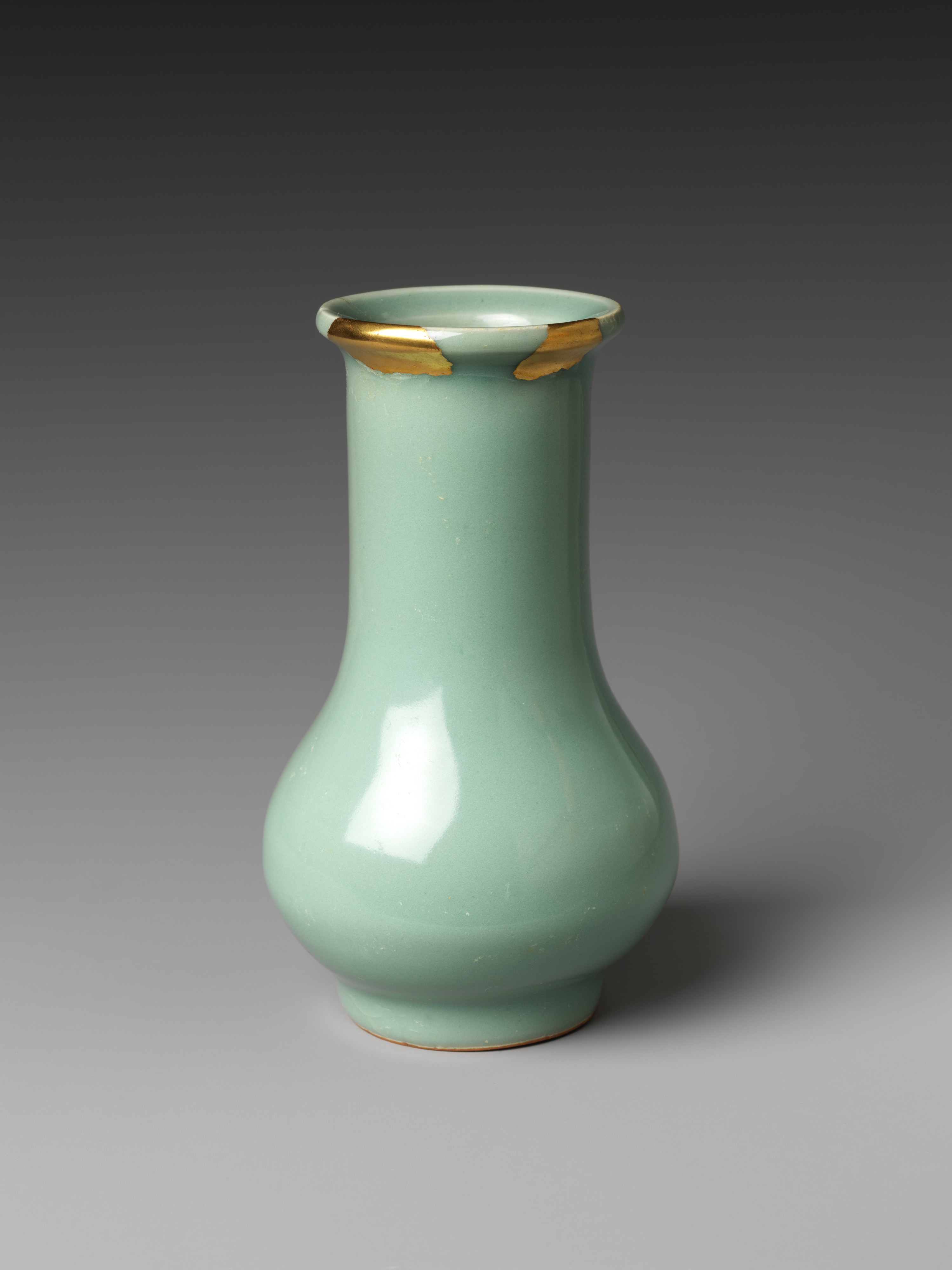 Petit vase Longquan céladon vert pâle, panse renflée, lèvre marquée de patches dorés.