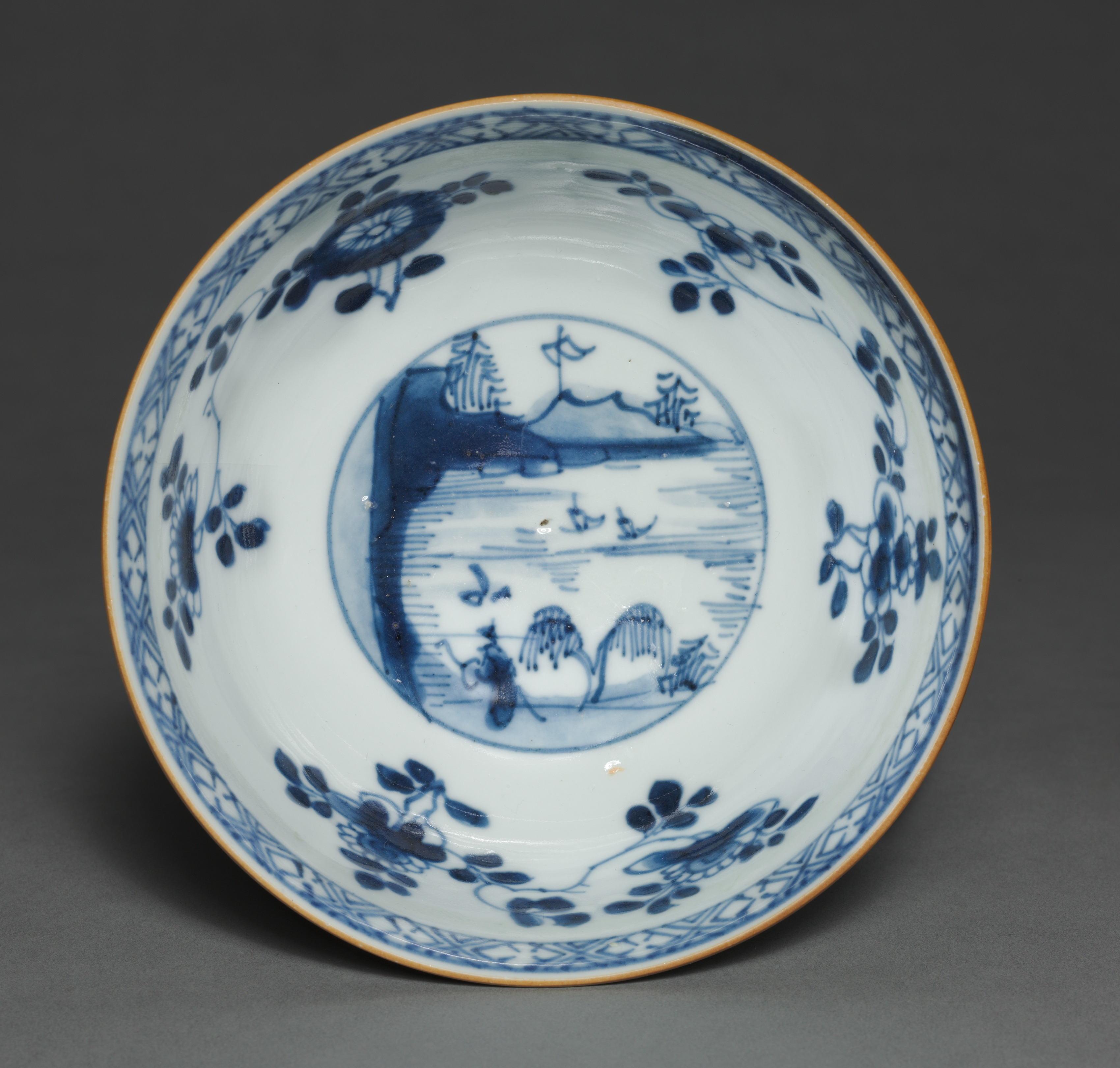 Bol en porcelaine chinoise à décor bleu et blanc, un médaillon réservé renfermant un paysage au milieu de rinceaux fleuris.