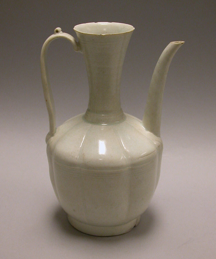 Aiguière en porcelaine blanc bleuté : col haut évasé, panse à côtes, anse, long bec courbe partant de l’épaule.