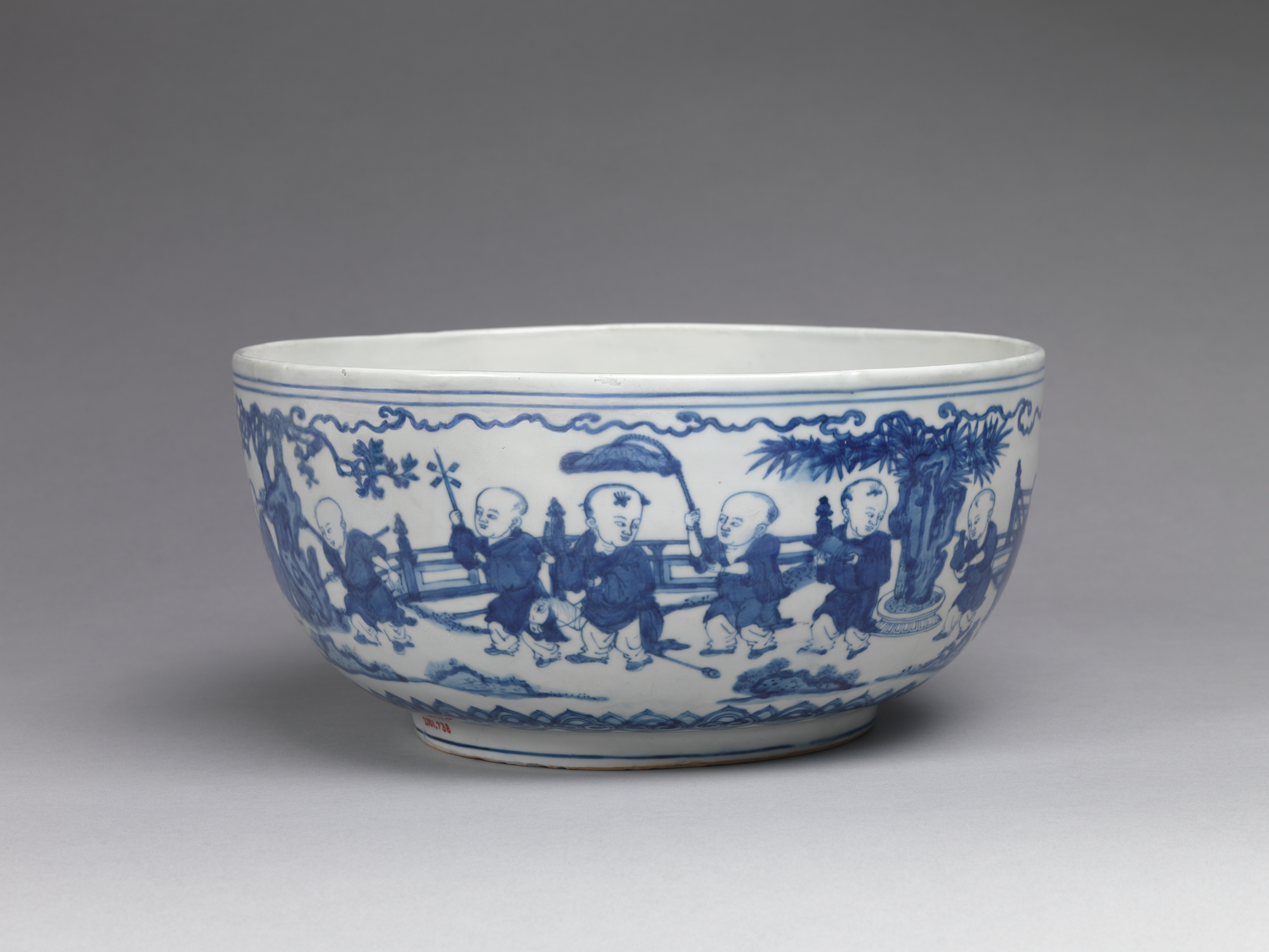 Grand bol en porcelaine blanche peinte en bleu de cobalt, décor de petits enfants jouant dans un jardin sur la paroi extérieure.