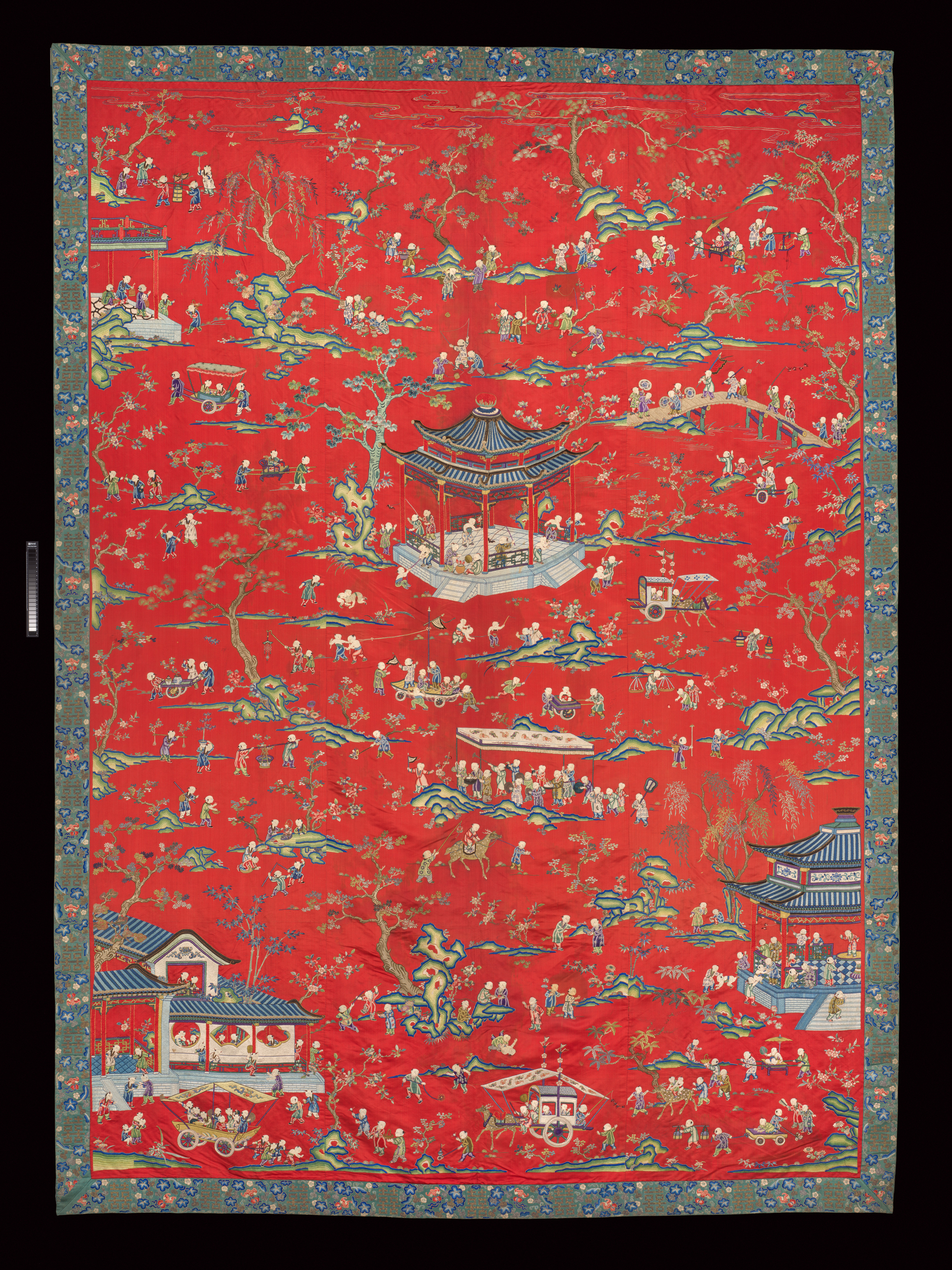Grande tenture de soie brodée polychrome figurant des dizaines de petits garçons à divers jeux dans un jardin.